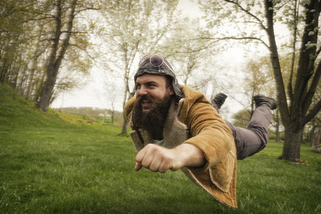 Bearded aviator soars through the air like an airplaneの写真素材