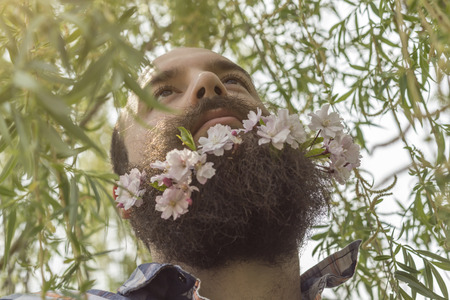 Flowers decorate the beard of this young man enjoying natureの写真素材