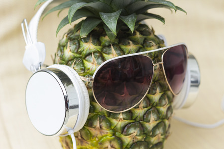 Cool pineapple with sunglasses and headphones in summer themed photoの写真素材