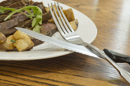 Sliced juicy skirt steak with potatoes and arugula garnishの写真素材