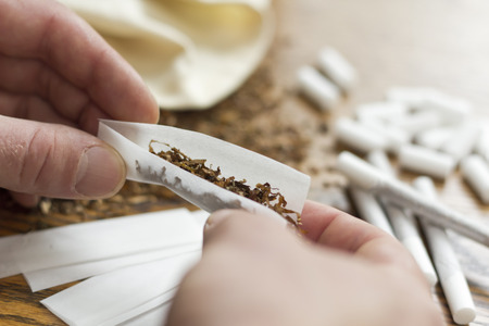 Rolling cigarettes with filters papers and plenty finely cut tobaccoの写真素材