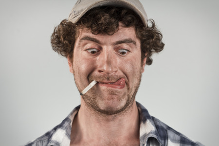 Hungry redneck licks his lips while smoking a cigaretteの写真素材