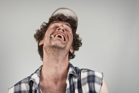 Laughing redneck burts into hysterics as he smokes his cigarette
