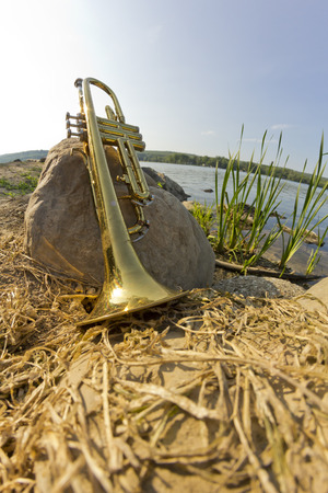 Summer Jazz trumpet in nature lying on rocks lakesideの写真素材