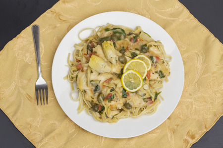 Italian chicken piccata schnitzel with artichoke hearts served on linguineの写真素材