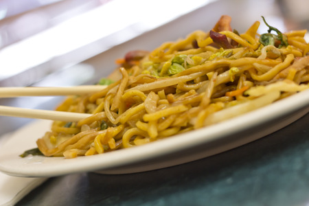 Eating Chinese pork lo mein noodles with chopsticksの写真素材