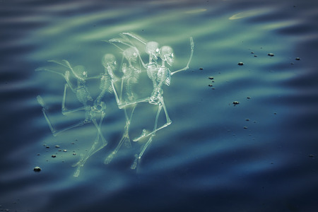 Scary dancing fairy skeletons on water backgroundの写真素材