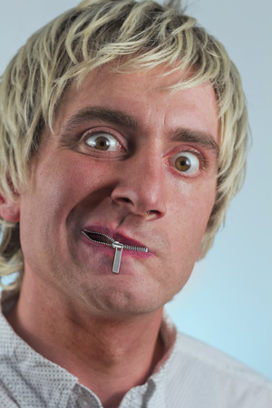 Zipper on mouth silences silly blonde haired manの写真素材