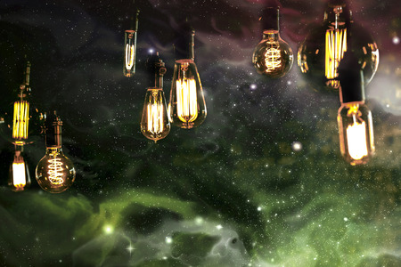 Edison style light bulbs against beautiful universe of stars and galaxiesの写真素材