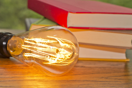 Decorative antique edison style filament light bulb and stack of booksの写真素材