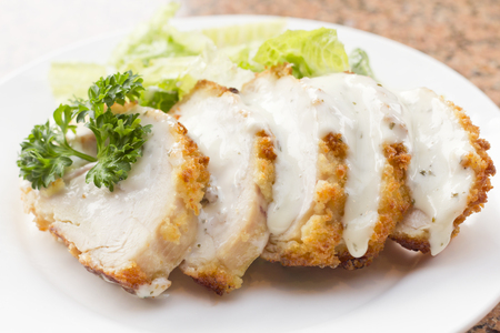 Sliced chicken cordon bleu with creamy sauce and romane leaf saladの写真素材