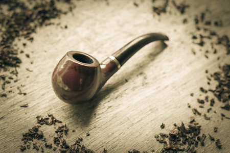 Tobacco pipe on rustic warn wood surface with spilled natural tobaccoの写真素材