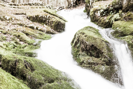 Misty waterfall deep in the woods cascading down the mossy rocks