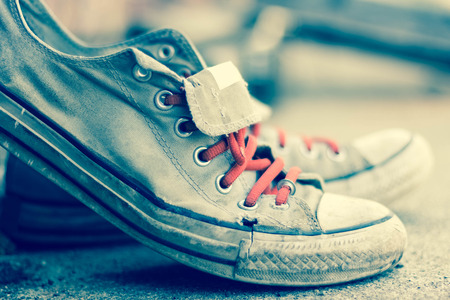 Pair of old worn classic sneakers leaning against a brick wallの写真素材