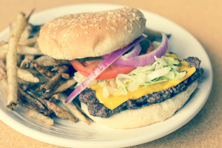 cheeseburger on sesame seed bun with lettuce tomato onions and potato skin friesの写真素材