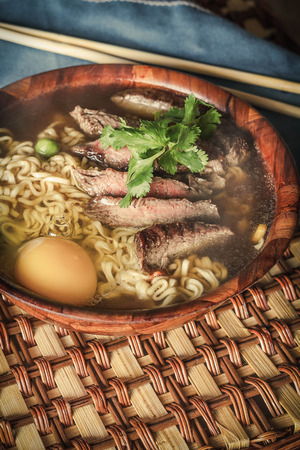 Beef ramen served Asian style. Raw egg cooks in steaming hot savory brothの写真素材