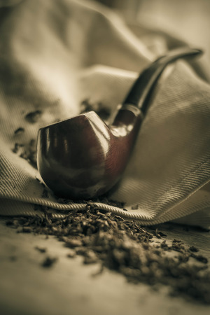 Tobacco pipe on rustic warn wood surface with spilled natural tobaccoの写真素材