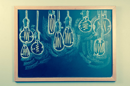Variety of antique edison style lightbulbs drawn on chalkboardの写真素材