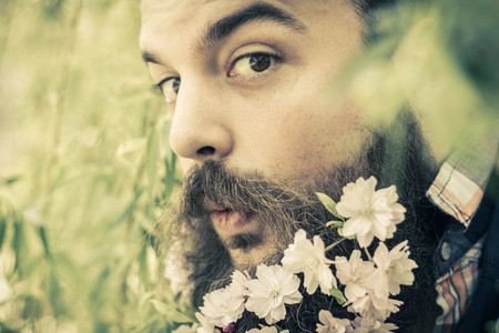 Flowers decorate the beard of this young man enjoying natureの写真素材