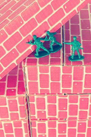 Green army men using teamwork to make progress up the toy brick stairsの写真素材