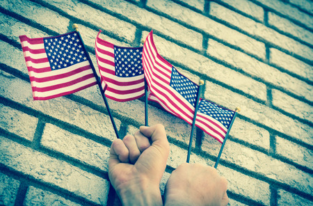 Fists clench small American flags in patriotic imageryの写真素材