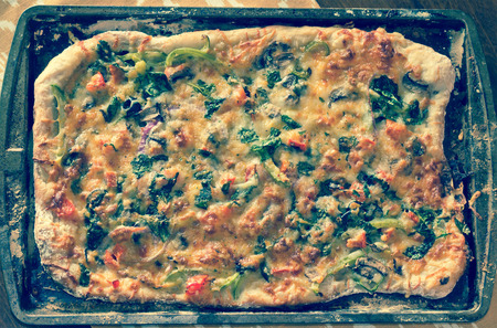 Home made artisan veggie pizza pie with onions peppers spinach and olives