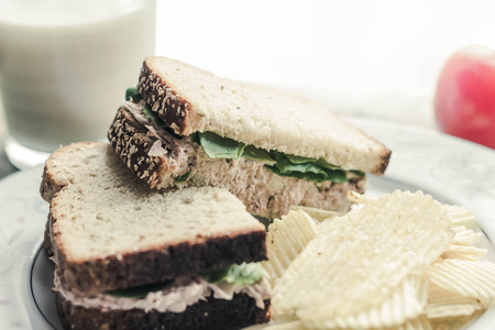 Tuna salad sandwich with ripple potato chips and a glass of milkの写真素材