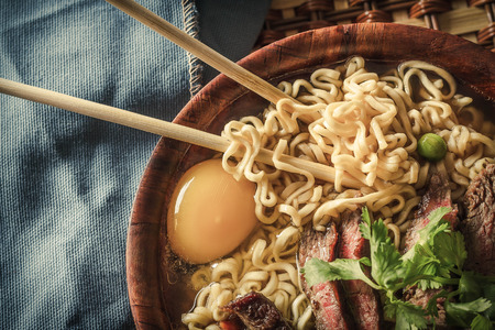 Beef ramen served Asian style. Raw egg cooks in steaming hot savory brothの写真素材