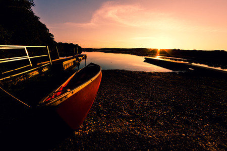 Red canoe on lake shore at dusk in fisheye nature shotの写真素材