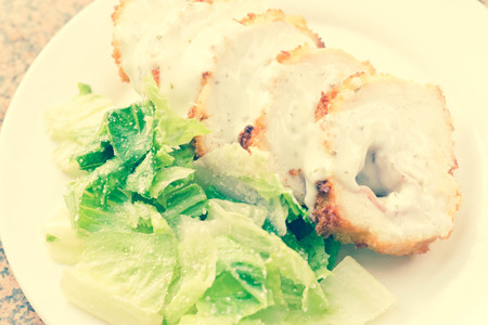 Sliced chicken cordon bleu with creamy sauce and romane leaf saladの写真素材