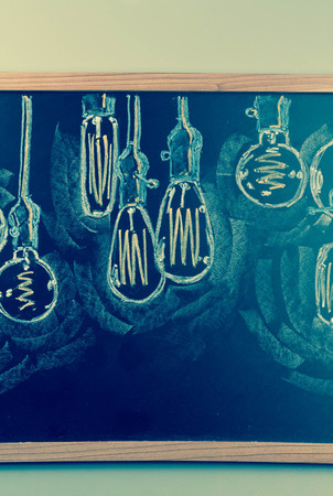 Variety of antique edison style lightbulbs drawn on chalkboardの写真素材