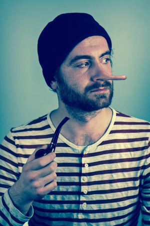 Lying bearded sailor grimacing while smoking a pipeの写真素材