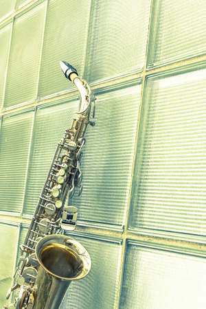 Lone old saxophone leans against brick wall outside abandoned jazz clubの写真素材
