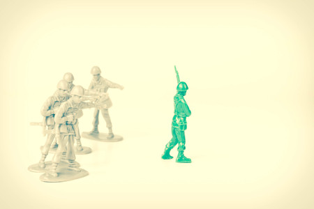 Gray toy soldiers pointing and bullying a green toy soldierの写真素材