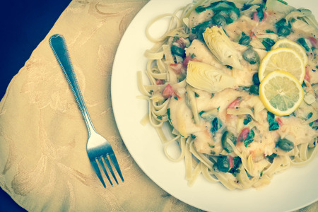 Italian chicken piccata schnitzel with artichoke hearts served on linguineの写真素材