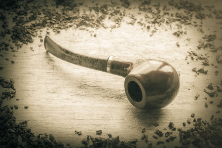 Tobacco pipe on rustic warn wood surface with spilled natural tobaccoの写真素材