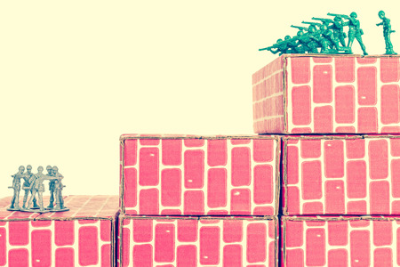 Gray toy army men up against impossible odds in uphill battleの写真素材