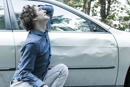 Silly man makes angry annoyed facial expression about dame to his carの写真素材