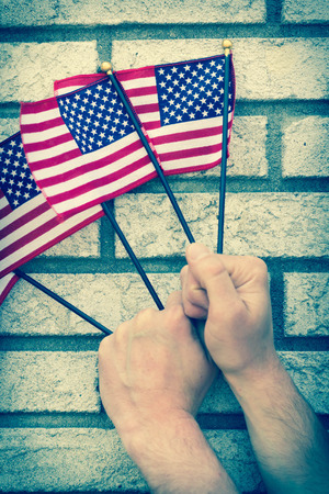 Fists clench small American flags in patriotic imageryの写真素材