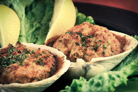 Stuffed seasoned clams garnished with romaine lettuce and lemon wedges on a rustic platterの写真素材