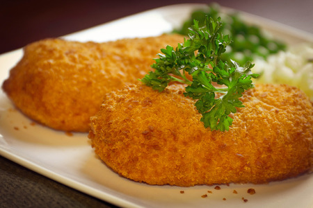 Breaded stuffed chicken cordon bleu with green peas white rice and parsley for garnishの写真素材