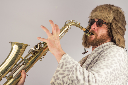 Bearded hipster plays jazz saxophone in leopard print bathrobeの写真素材