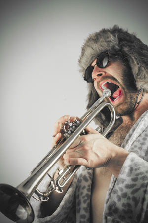 Bearded hipster plays jazz trumpet in leopard print bathrobeの写真素材