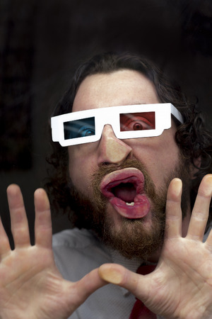 Silly bearded man wearing 3D glasses smooshing face against glass