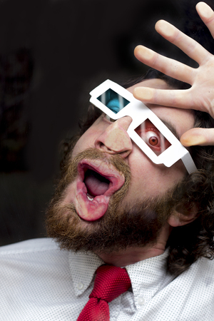 Silly bearded man wearing 3D glasses smooshing face against glassの写真素材