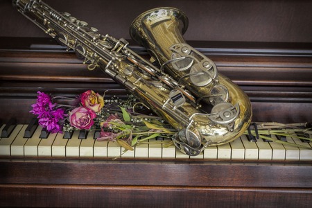 Old and worn Jazz saxophone and piano with dried rosesの写真素材