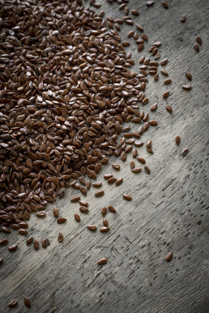 Close up flax seed on rustic worn wooden table surfaceの写真素材