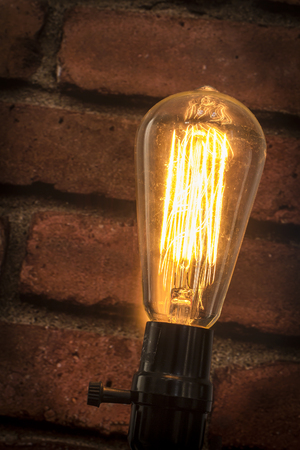 Decorative antique edison style filament light bulb with brick wall background