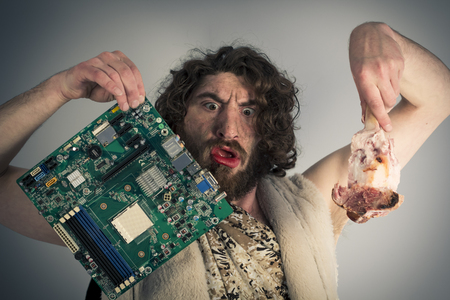Silly confused caveman chooses between food and modern technologyの写真素材