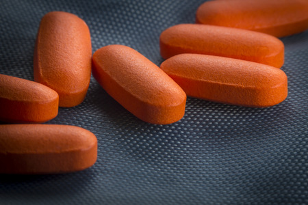 Macro close up orange pain killer pills on blue backgroundの写真素材